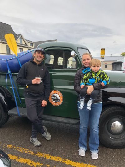 Zoo Town Surfers founded Jason Shreder is pictured with his wife and son in front of their iconic green Zoo Town Surfers vintage truck. There is a raft in the back.