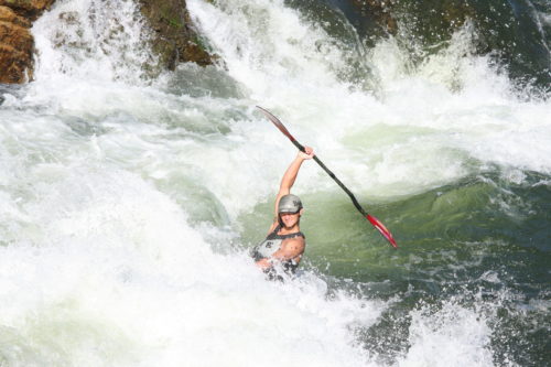 a kayaker holds his paddle on the alberton gorge. He is submerged in a wave and all you see is the paddle and his torso sticking out.