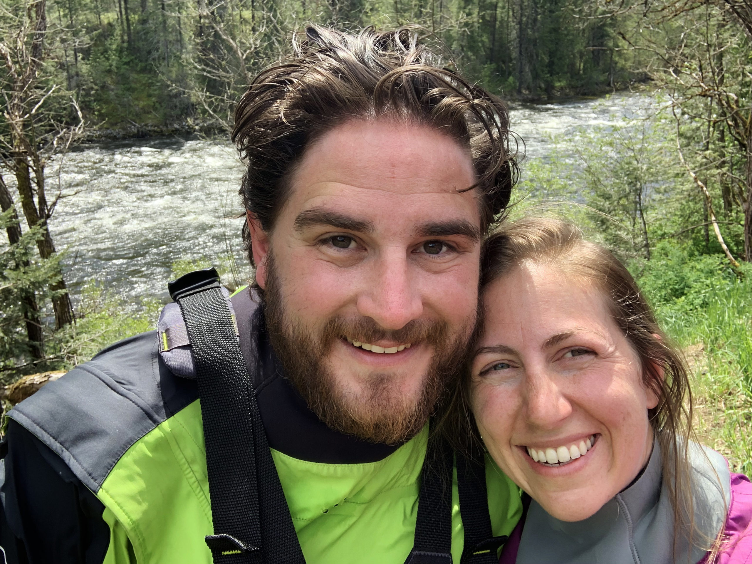 Whitewater rafting near Missoula MT. Ian and Megan the owners of Zoo Town Surfers are smiling in their drysuits with the Lochsa River in the background.